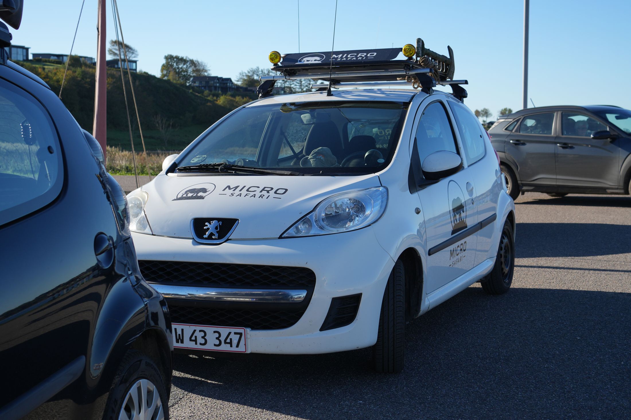 Hvid Microsafari-bil med tagbagage ved havnen