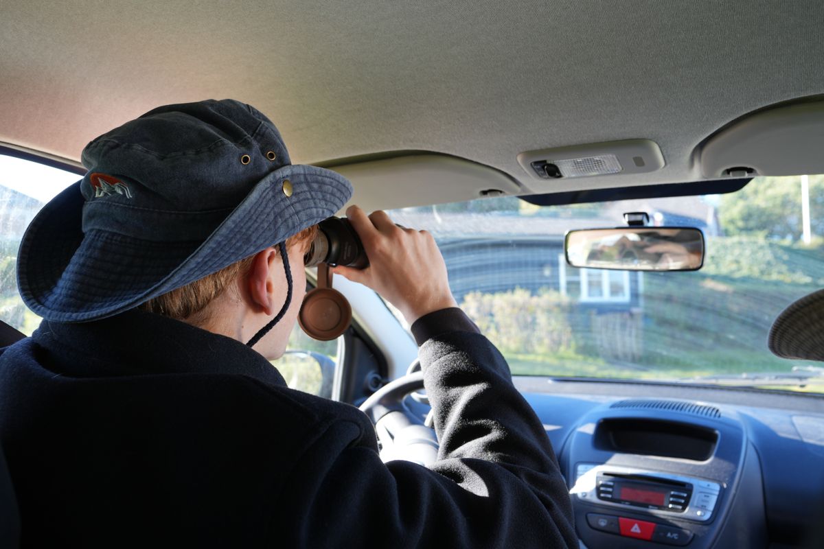 Deltager kigger i kikkert fra bilen